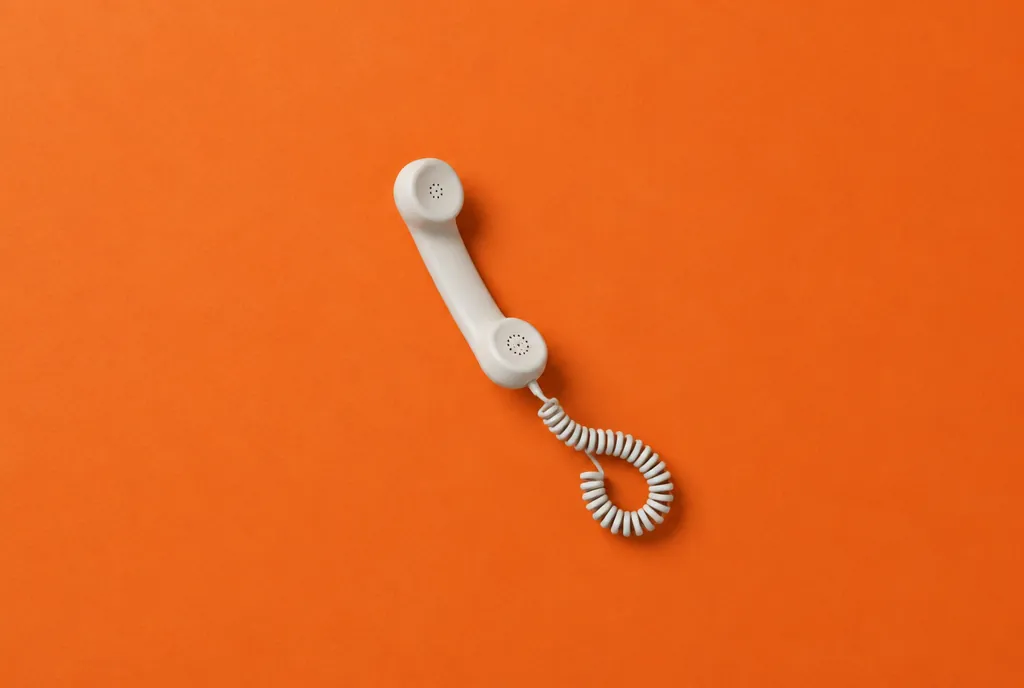 Vit telefonlur med spiralsladd mot orange bakgrund